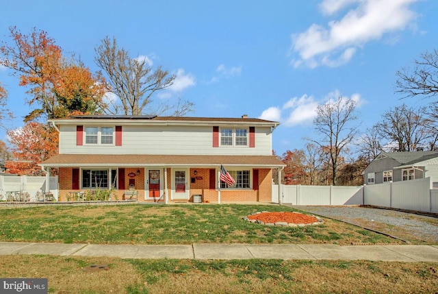 view of front facade featuring solar panels, a porch, and a front lawn