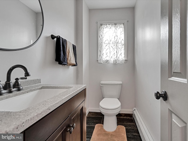 bathroom with baseboard heating, hardwood / wood-style floors, vanity, and toilet