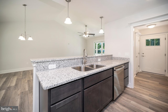 kitchen with sink, vaulted ceiling, stainless steel dishwasher, light stone countertops, and light wood-type flooring