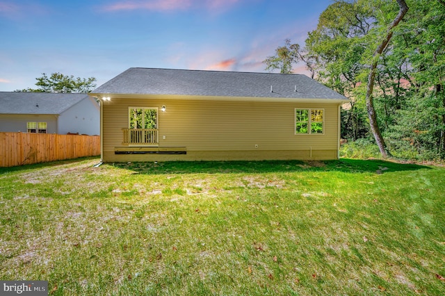 back house at dusk with a lawn