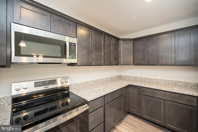 kitchen featuring dark brown cabinetry, light stone counters, light hardwood / wood-style floors, and appliances with stainless steel finishes