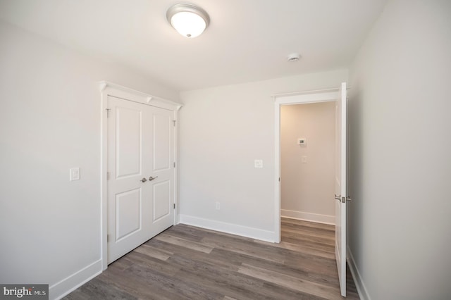 unfurnished bedroom featuring a closet and dark wood-type flooring