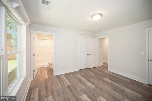 unfurnished bedroom featuring hardwood / wood-style flooring and ensuite bath