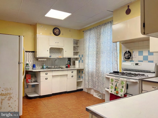 kitchen with white cabinets, decorative backsplash, white appliances, and sink