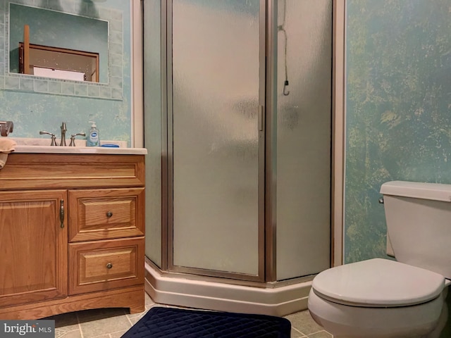 bathroom featuring tile patterned floors, vanity, toilet, and a shower with shower door