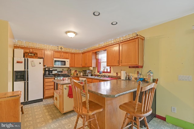 kitchen featuring a breakfast bar, white appliances, kitchen peninsula, and sink