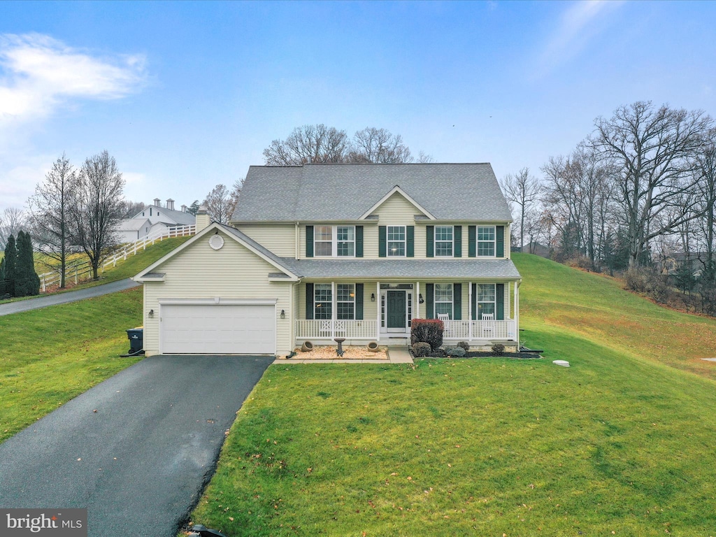 colonial inspired home with covered porch, a garage, and a front lawn