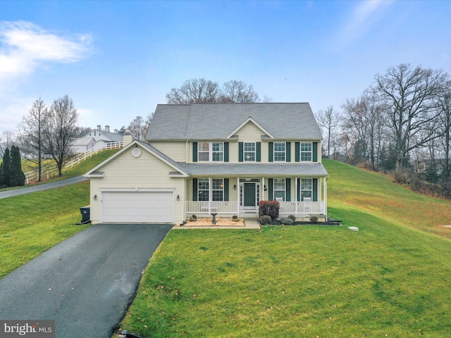 colonial inspired home with covered porch, a garage, and a front lawn