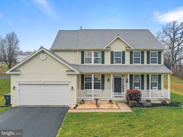 view of front of property with a porch, a garage, and a front lawn