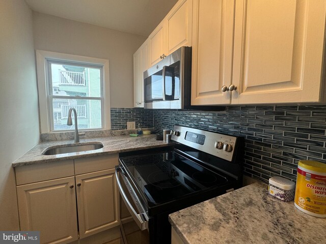 kitchen featuring tasteful backsplash, white cabinetry, sink, and stainless steel appliances