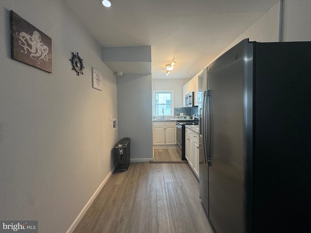 6406 Coastal Hwy Unit 201, Ocean City, MD 21842 - kitchen featuring appliances with stainless steel finishes, light wood finished floors, white cabinetry, decorative backsplash, and light countertops