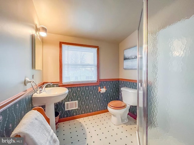 bathroom featuring a shower with door, lofted ceiling, and toilet