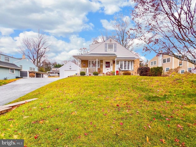 view of front facade featuring an outbuilding, a garage, a front lawn, and covered porch