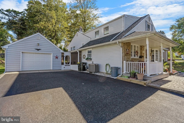 view of front of property with a porch, a garage, central air condition unit, and an outbuilding