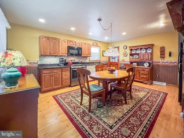 kitchen with white dishwasher, sink, light hardwood / wood-style flooring, stainless steel gas range, and decorative light fixtures