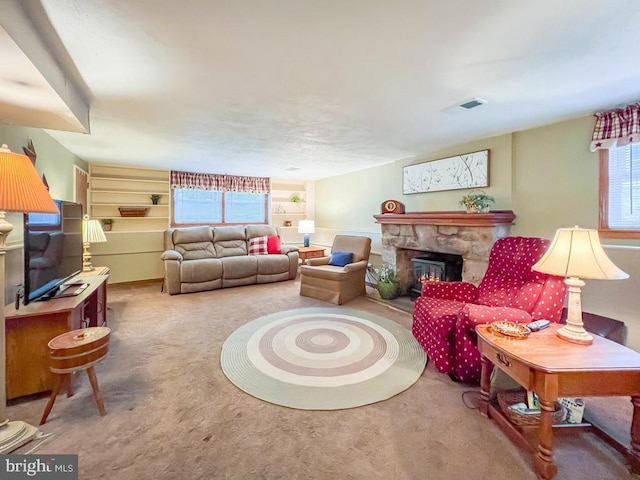 carpeted living room featuring a stone fireplace