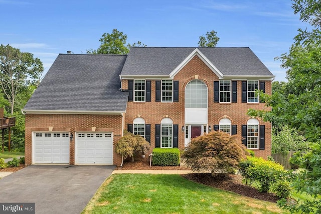 colonial-style house featuring a garage and a front yard