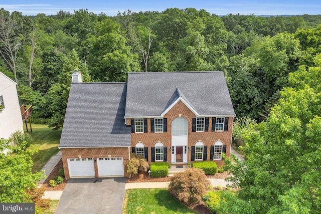 colonial home with a garage and a front lawn