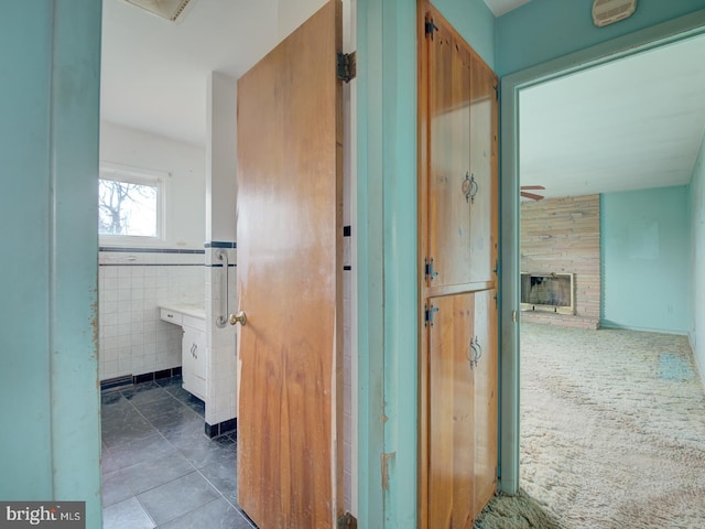 corridor with dark tile patterned floors and tile walls