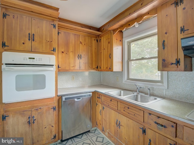 kitchen featuring dishwasher, sink, white oven, tasteful backsplash, and exhaust hood