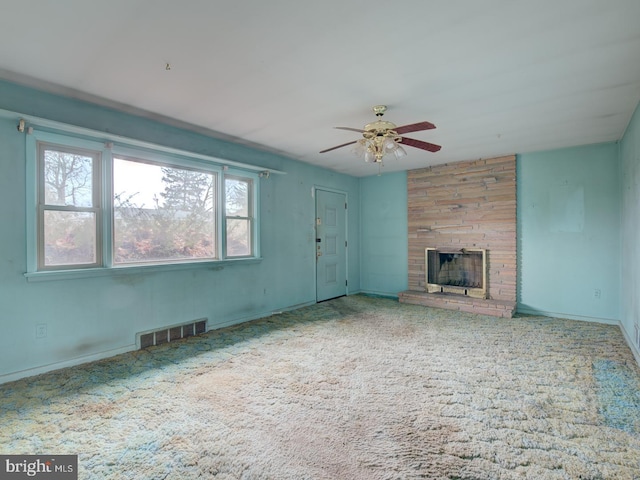 unfurnished living room with carpet, ceiling fan, and a large fireplace