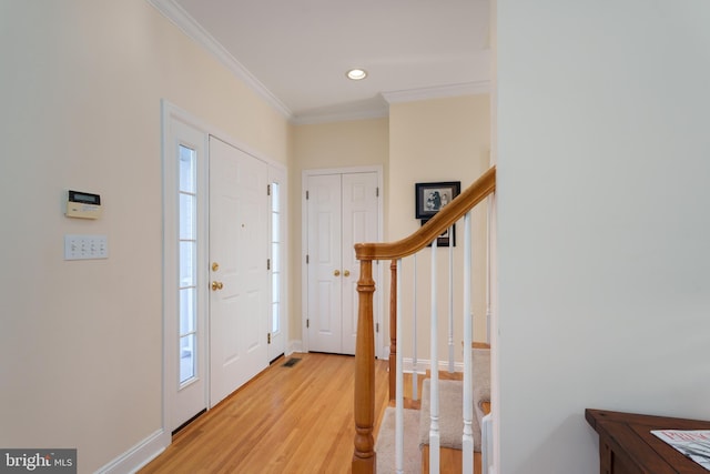 foyer entrance featuring light hardwood / wood-style flooring, a healthy amount of sunlight, and crown molding