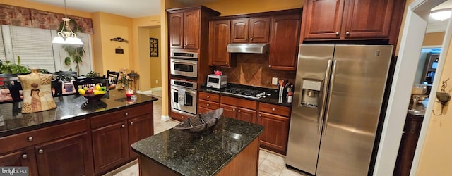 kitchen featuring hanging light fixtures, light tile patterned floors, appliances with stainless steel finishes, tasteful backsplash, and a kitchen island