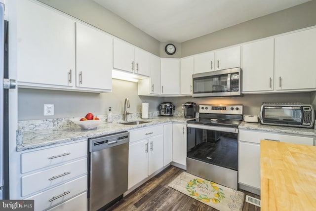 kitchen featuring wood counters, appliances with stainless steel finishes, sink, dark hardwood / wood-style floors, and white cabinetry