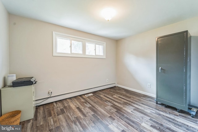 unfurnished room featuring dark hardwood / wood-style floors and a baseboard heating unit