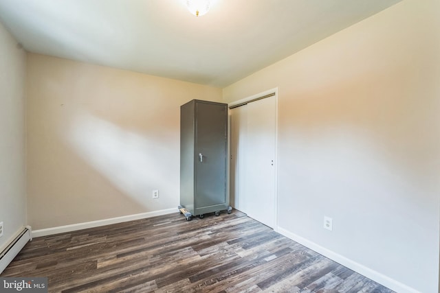 unfurnished room featuring dark hardwood / wood-style floors and a baseboard heating unit