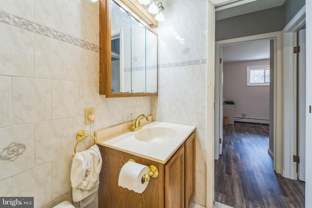 bathroom with hardwood / wood-style floors, vanity, a baseboard radiator, and tile walls