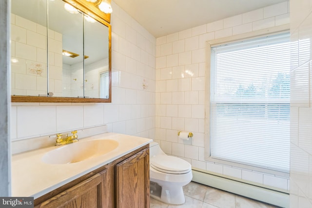 bathroom with baseboard heating, tile patterned floors, toilet, vanity, and tile walls