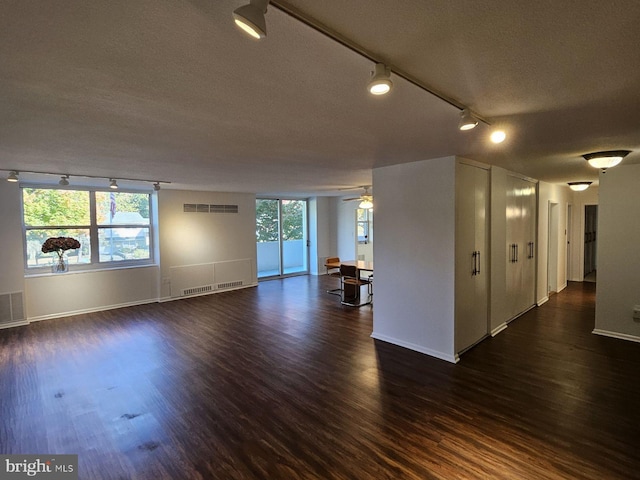 spare room with a textured ceiling, ceiling fan, dark wood-type flooring, and track lighting