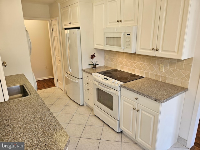 kitchen with white cabinetry, white appliances, light tile patterned floors, and tasteful backsplash