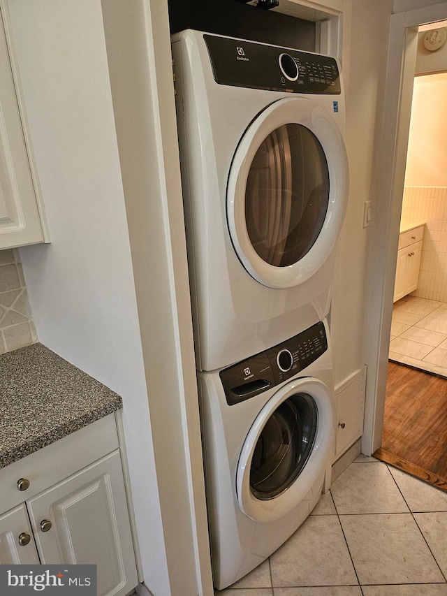 laundry room featuring light hardwood / wood-style flooring and stacked washer / dryer