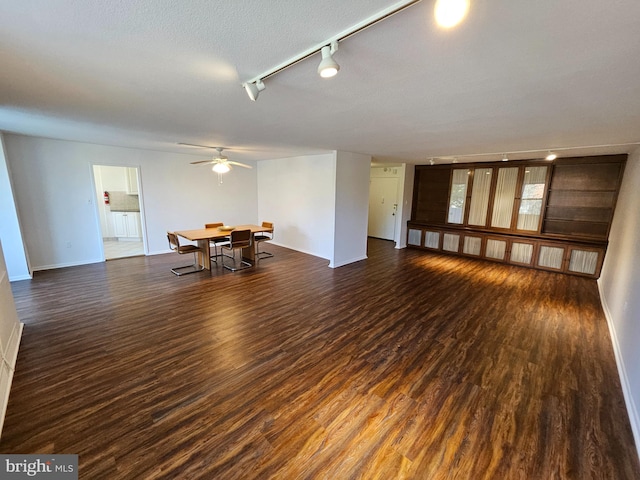 interior space with a textured ceiling, dark hardwood / wood-style floors, track lighting, and ceiling fan