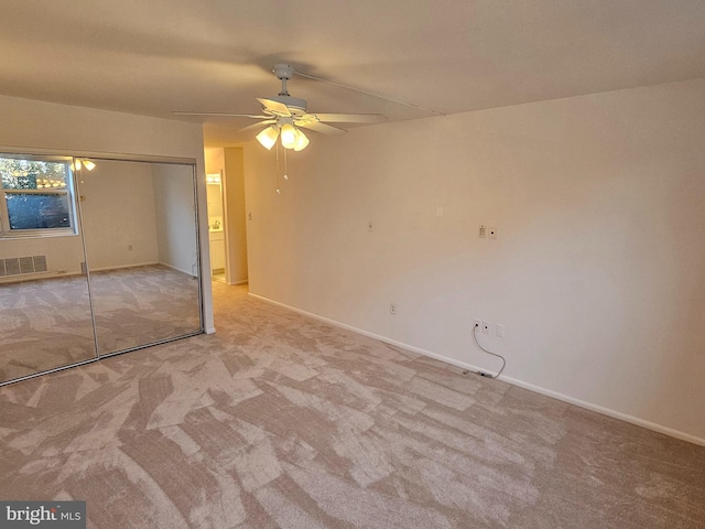 unfurnished bedroom with ceiling fan, light carpet, and a closet