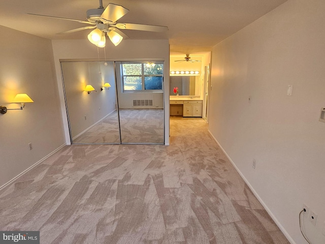 unfurnished bedroom with a closet, light colored carpet, and ceiling fan