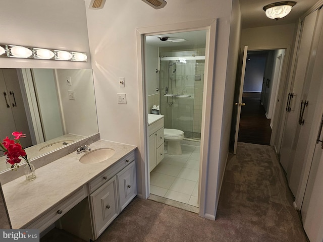 bathroom featuring tile patterned flooring, vanity, toilet, and a shower with door