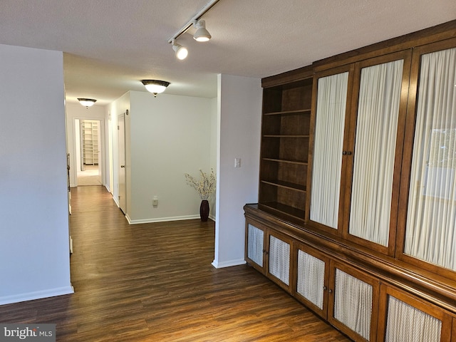 hall with a textured ceiling, track lighting, and dark hardwood / wood-style floors