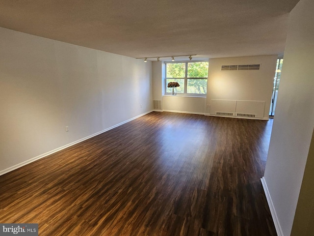 unfurnished room with a textured ceiling, dark hardwood / wood-style flooring, and track lighting