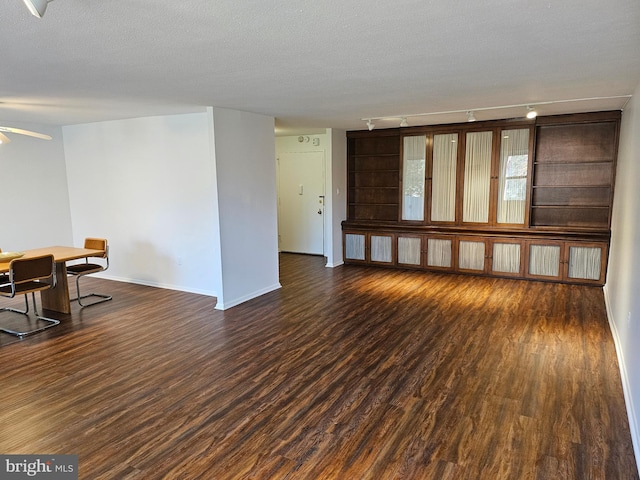 spare room with ceiling fan, dark hardwood / wood-style flooring, a textured ceiling, and track lighting