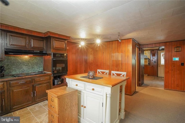 kitchen with wood counters, wood walls, backsplash, light carpet, and black appliances