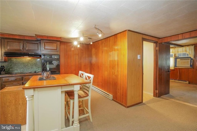 kitchen with butcher block countertops, baseboard heating, a breakfast bar area, and wood walls