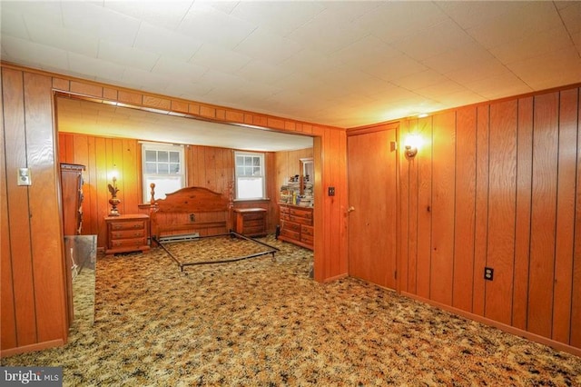 carpeted bedroom featuring wood walls and a baseboard heating unit