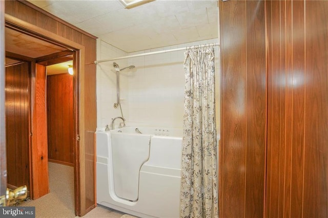 bathroom featuring wood walls and shower / bath combo with shower curtain