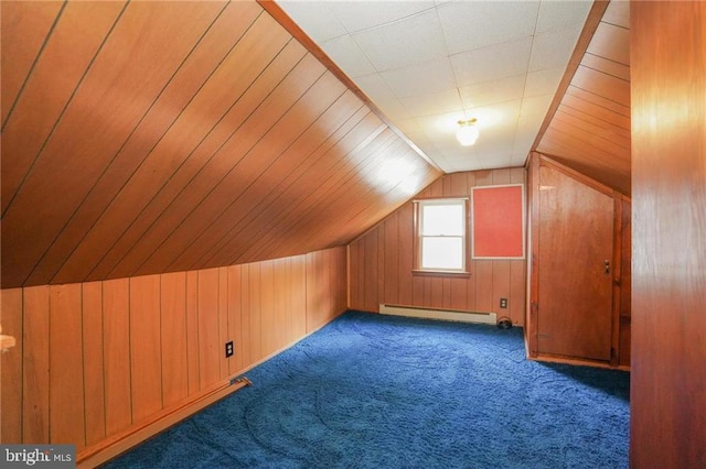 additional living space with a baseboard radiator, dark carpet, and wooden walls