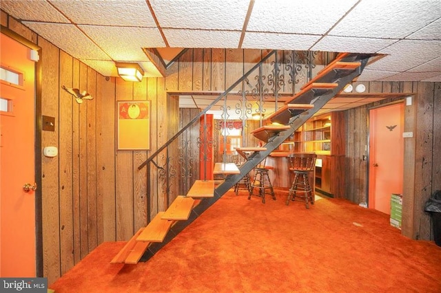 basement with carpet and wooden walls