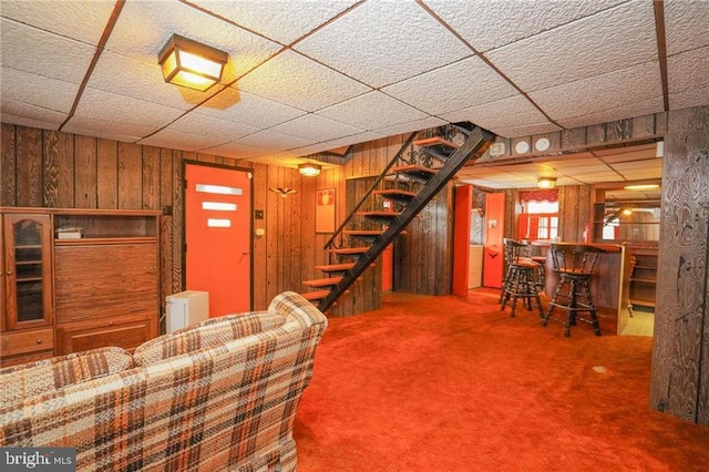 unfurnished living room with indoor bar, carpet floors, and wood walls