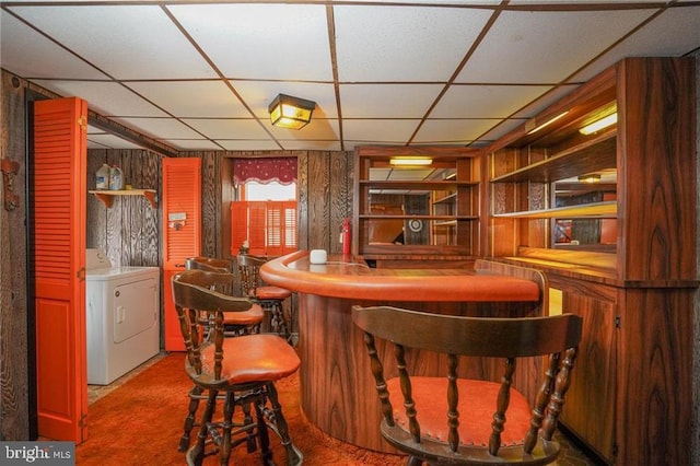 bar featuring a paneled ceiling, washer and dryer, carpet, and wooden walls